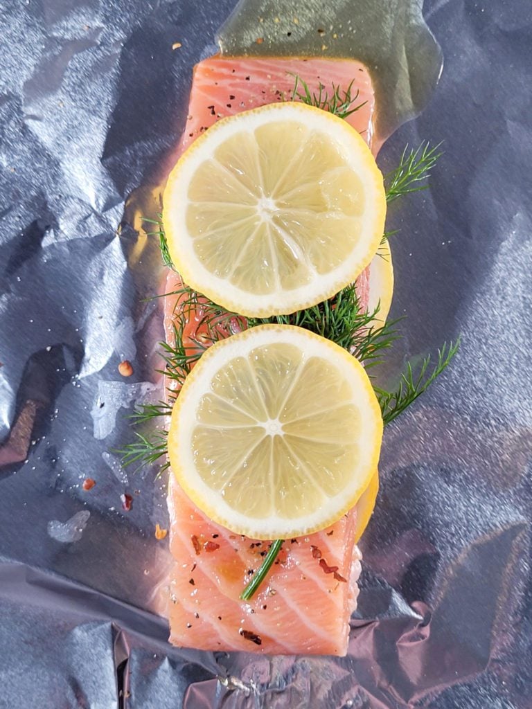 Raw salmon with lemon and dill on tinfoil.